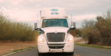 White TSI Tractor on 2 Lane Highway with Headlights On