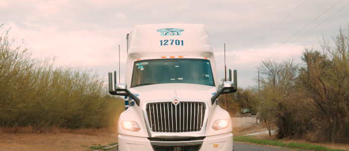 White TSI Tractor on 2 Lane Highway with Headlights On