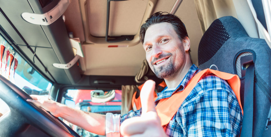 Truck driver sitting in cabin giving thumbs-up