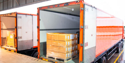 Package Boxes Loading into Cargo Container. Trailer Truck Parked