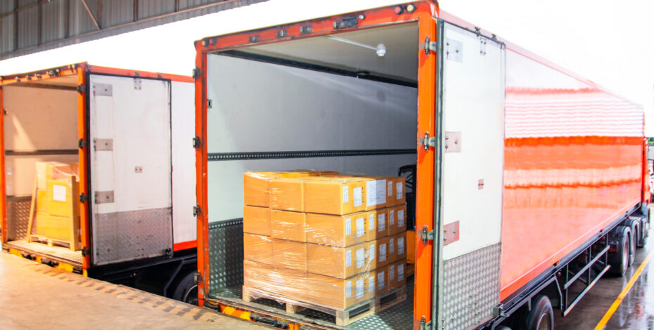 Package Boxes Loading into Cargo Container. Trailer Truck Parked