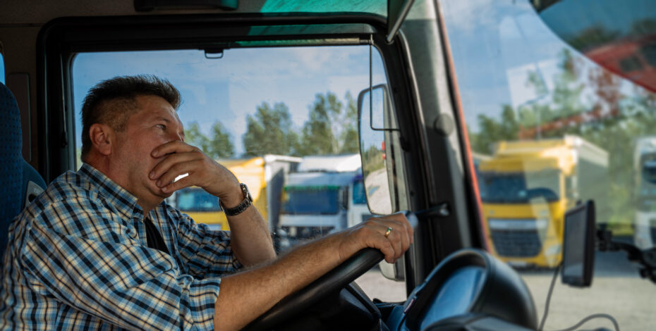 Man looking worried in truck, looking out over wheel