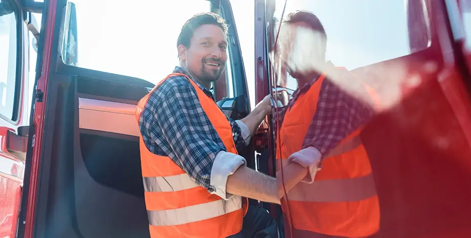 Truck driver standing in doorway of red truck